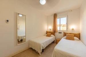 a bedroom with two beds and a mirror at Apartamento Las Gaviotas 9A in Tarifa