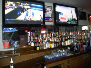 Eine Bar mit zwei Fernsehern über einer Bar mit Flaschen Alkohol in der Unterkunft Wasco Inn in Wasco