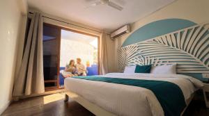 a bedroom with a bed and two people sitting on a porch at Kue Hotel Maafushi in Maafushi