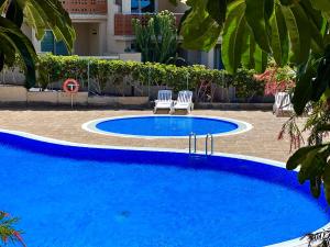 a large blue swimming pool with two chairs next to it at 2-bedroom apartment with terrace VistaRoja in Granadilla de Abona