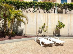 a row of white benches sitting next to a wall at 2-bedroom apartment with terrace VistaRoja in Granadilla de Abona
