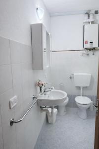 a white bathroom with a toilet and a sink at Appartamento Alta Valle Maira - Midia in Villaro +1 photo