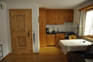 a kitchen with wooden cabinets and a bed in a room at Chesa Viletta in La Punt-Chamues-ch