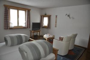 a living room with white furniture and a tv at Chesa Viletta in La Punt-Chamues-ch