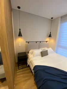 a bedroom with a large white bed and two lights at Apartasuite Cowork in Bogotá