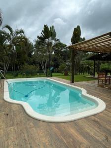 a large swimming pool in a yard with a wooden deck at Sítio Funilândia - MG in Funilândia