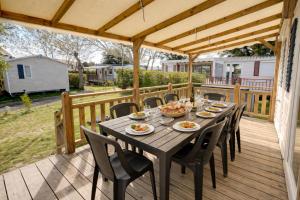 a wooden deck with a wooden table and chairs at Mobilhome L'Instant Vacances - La Plage in Mimizan-Plage