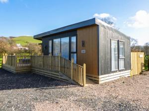 a tiny house with a large deck on a gravel lot at Dawn's Rest in Rhayader
