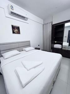 a white bedroom with a white bed with a air conditioner at Almasar Hotel in Maţār as Sīb ad Duwalī +35 photos