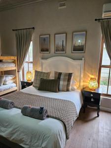a bedroom with two beds and two lamps and windows at The Merino Guest House in Beaufort West