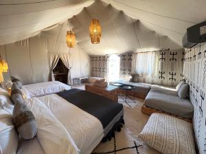 a bedroom with a large bed and a couch at dreaming desert Luxury Camp in Adrouine