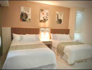 two beds in a hotel room with white sheets at Baba Staytion 1-2-3 of SMDC Style Condo in Iloilo City