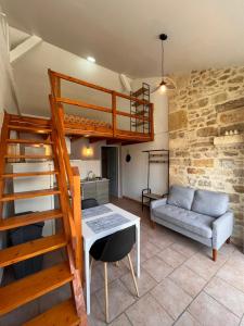 a room with a loft bed and a table and a couch at Gîtes de la chocolaterie in Viré