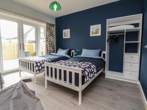 two beds in a bedroom with blue walls at Mikes Place On The Cove in Rhyl
