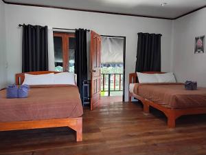 a bedroom with two beds and a door to a balcony at LUCKY PAI Resort&Hostel in Pai