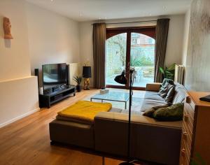 a living room with a couch and a flat screen tv at Spacious Design Home with Garden near Centre in Bruges