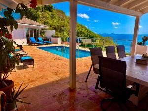a patio with a table and chairs and a pool at A Newly Renovated Luxury 4 Bed Villa in Tortola Island