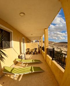 a balcony with green lounge chairs on a building at B&B petrafarmhouse in Wadi Musa