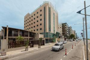 a car driving down a street with a tall building at Ibis Styles Macaé in Macaé