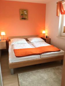 een slaapkamer met een bed met een oranje muur bij Ruhige Ferienwohnung in Graal Müritz (EW) in Graal-Müritz