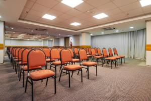 a conference room with orange chairs and a screen at Ibis Styles Macaé in Macaé +90 photos