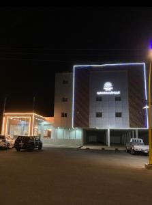 a building with a lit up sign on it at night at ثار بارك للشقق المخدومة in Qushayya