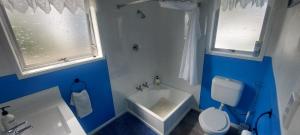 a blue and white bathroom with a toilet and a sink at Fantastic Two Bedroom Unit in Whakatane