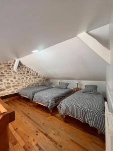 two beds in a attic room with wooden floors at Gîtes de la chocolaterie in Viré