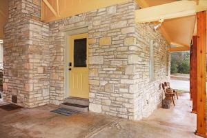 a stone house with a yellow door and a patio at Mi Rancho in Wimberley