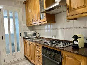 a kitchen with wooden cabinets and a stove top oven at Habitación privada en apartamento compartido junto al Aeropuerto y Fira Barcelona in El Prat de Llobregat +13 photos