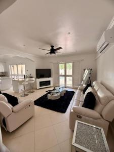 a living room with white furniture and a ceiling fan at Villa Ray in Gros Islet