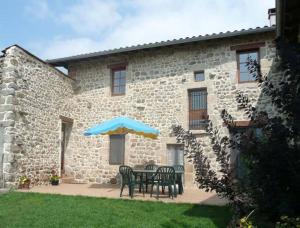 a table with chairs and an umbrella in front of a building at gite La Fermette in Valprivas