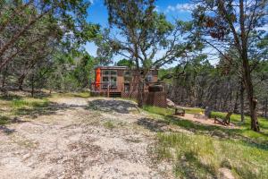 a cabin in the woods with a dirt road and trees at Martha at the Bend in Wimberley