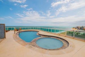 a swimming pool on a balcony with a view of the ocean at Ibis Styles Macaé in Macaé
