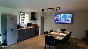 a kitchen with a table with chairs and a tv on the wall at Cozy Box in Agapia