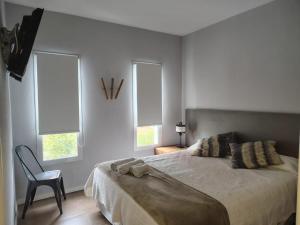a bedroom with a bed with a chair and windows at O2 Hotel Villa Gesell in Villa Gesell