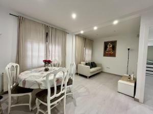 a white dining room with a table and a couch at Habitación privada en apartamento compartido junto al Aeropuerto y Fira Barcelona in El Prat de Llobregat