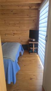 a bedroom with wooden walls and a bed and a television at Romantic Getaway Peace and a Unique View in Quillota