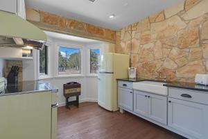 a kitchen with white cabinets and a stone wall at Milk Bath Springs Cottage in Dripping Springs
