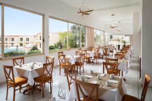 a restaurant with tables and chairs and large windows at The Freij Resort in Ayia Napa