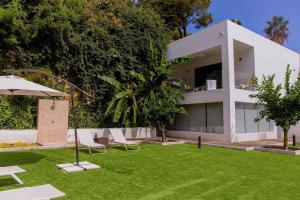 a house with a lawn with chairs and an umbrella at BLUESEA Dimona Suites in Torremolinos