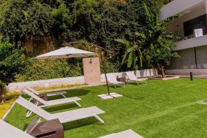a lawn with chairs and an umbrella on it at BLUESEA Dimona Suites in Torremolinos