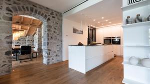 a kitchen with white cabinets and a stone wall at Villa Valentina by Rent All Como in Civenna +30 photos