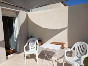 a patio with two white chairs and a table at Giannis' House in Polichnítos