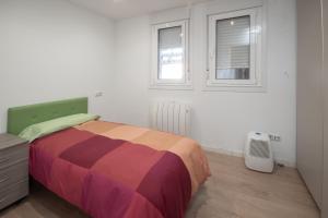 a bedroom with a bed with a colorful blanket and two windows at AG Piso Fogar Carballo, 3 habitaciones in Carballo