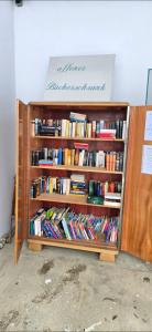 a wooden book shelf filled with books at Pension Mittendrin in Langenschönbichl