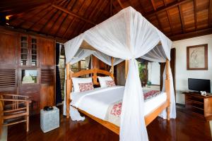 a bedroom with a bed with a canopy at Canang Sari Uluwatu Villas Bali in Uluwatu