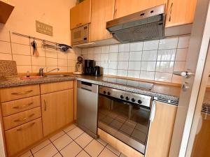 a kitchen with wooden cabinets and a stove top oven at Ferienwohnung De Diek 103 in Dorum-Neufeld