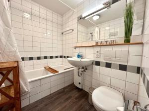a bathroom with a sink and a toilet and a tub at Ferienwohnung De Diek 103 in Dorum-Neufeld +4 photos
