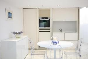 a white kitchen with a white table and chairs at Rooftop luxury apartment in Capri +6 photos
